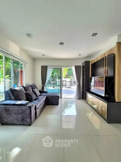 Spacious living room with modern decor and large windows overlooking a serene garden view.