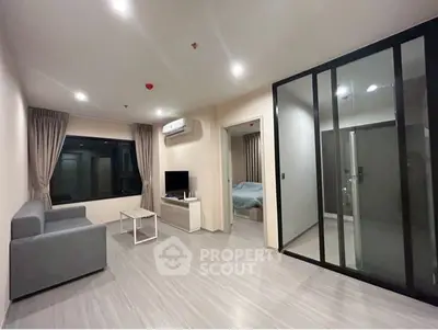 Modern living room with sleek design and glass partition leading to bedroom