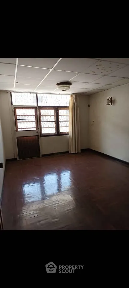 Spacious empty room with wooden flooring and large windows, ideal for customization.