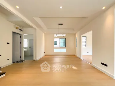 Spacious open-plan living area with modern lighting and wooden flooring.