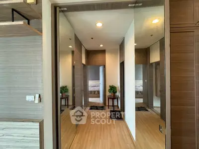 Modern hallway with wooden flooring and mirrored walls in a stylish apartment.