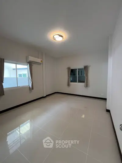 Spacious empty room with large windows and modern lighting, perfect for customization.