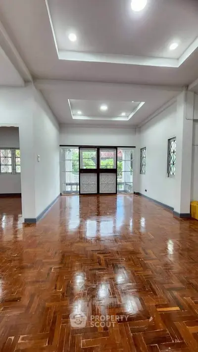 Spacious living room with polished wooden floors and large windows for natural light.