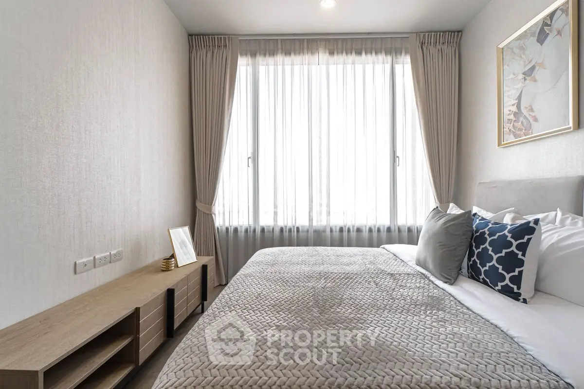 Modern bedroom with stylish decor and large window offering natural light