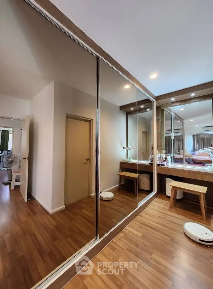 Spacious bedroom with mirrored closet doors and elegant wooden flooring