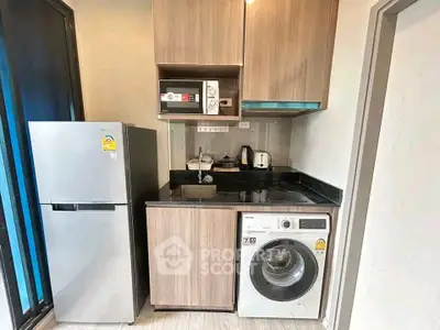Modern compact kitchen with appliances including fridge, microwave, and washing machine in stylish apartment.