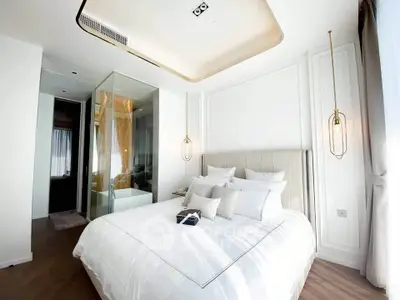 Luxurious modern bedroom with elegant lighting and glass-enclosed bathroom, featuring plush bedding and stylish decor.