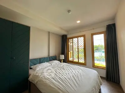 Cozy bedroom with large window and modern decor, offering a serene view.