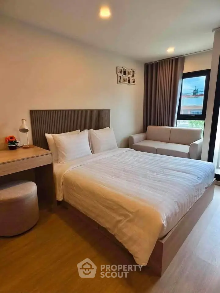 Modern bedroom with cozy bed, stylish decor, and natural light from large window.