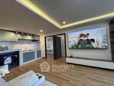 Modern living room with open kitchen, featuring a large TV and washing machine, ideal for urban living.