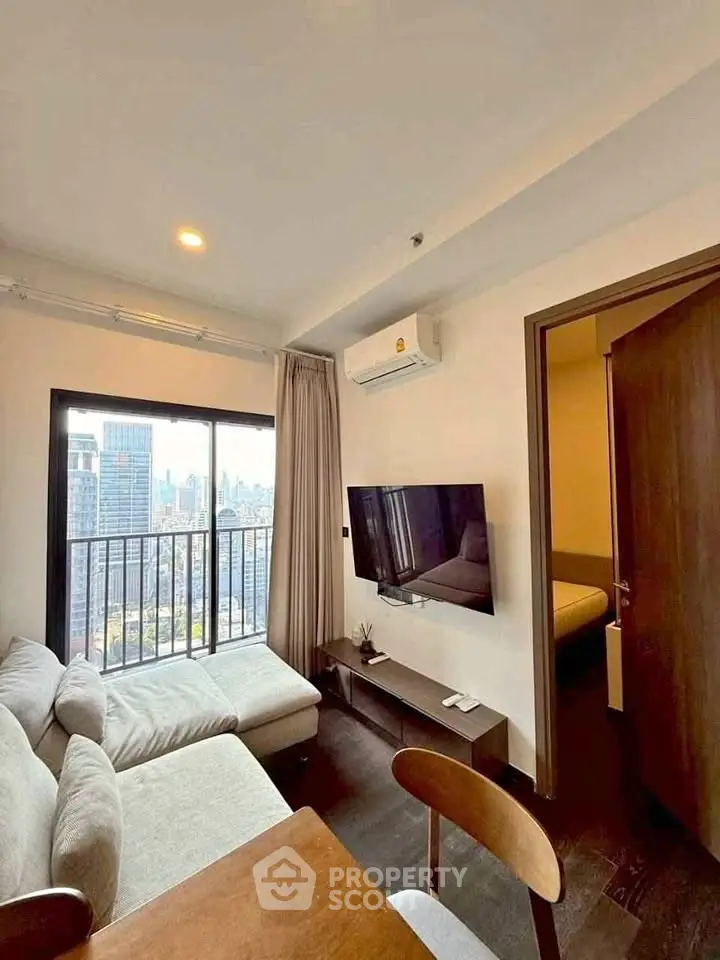 Modern living room with city view, featuring a cozy sofa and wall-mounted TV in a high-rise apartment.
