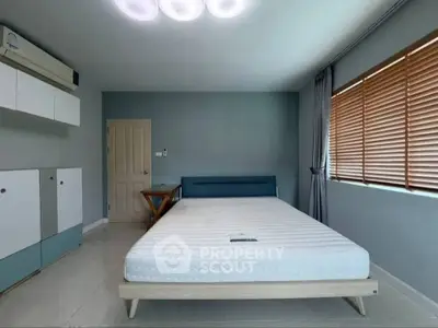 Spacious bedroom with modern minimalist design and ample natural light.