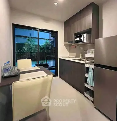 Modern kitchen with sleek cabinets and dining area overlooking a lush garden view.