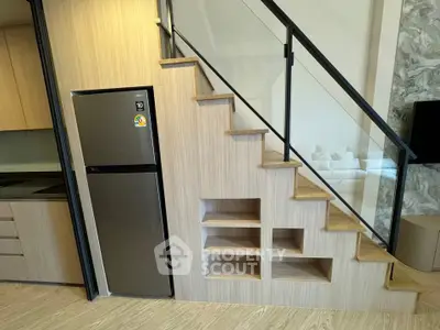 Modern kitchen with sleek fridge under stylish staircase storage solution