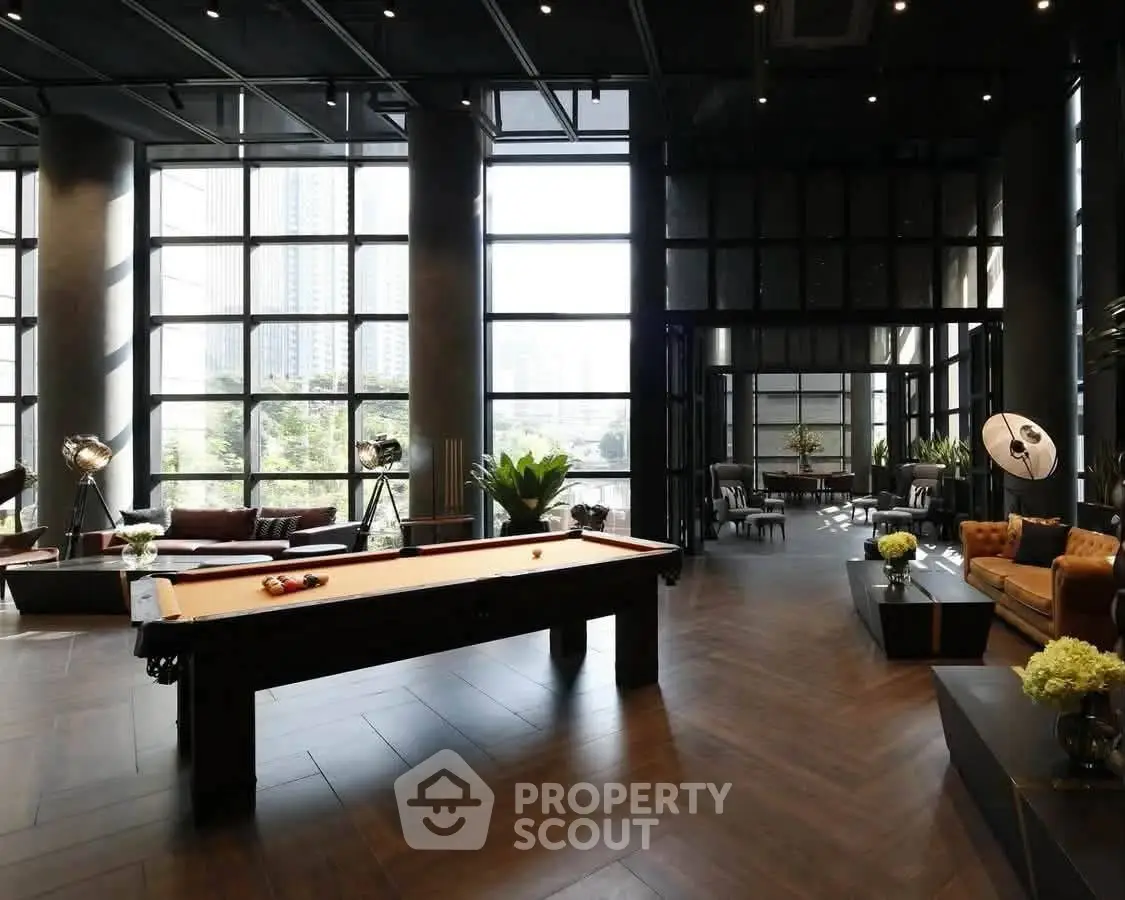 Luxurious modern living space with pool table and floor-to-ceiling windows offering stunning city views.