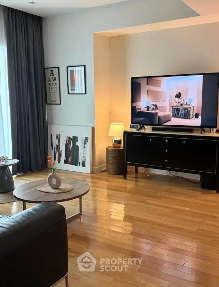 Stylish living room with wooden flooring, modern decor, and large TV for entertainment.