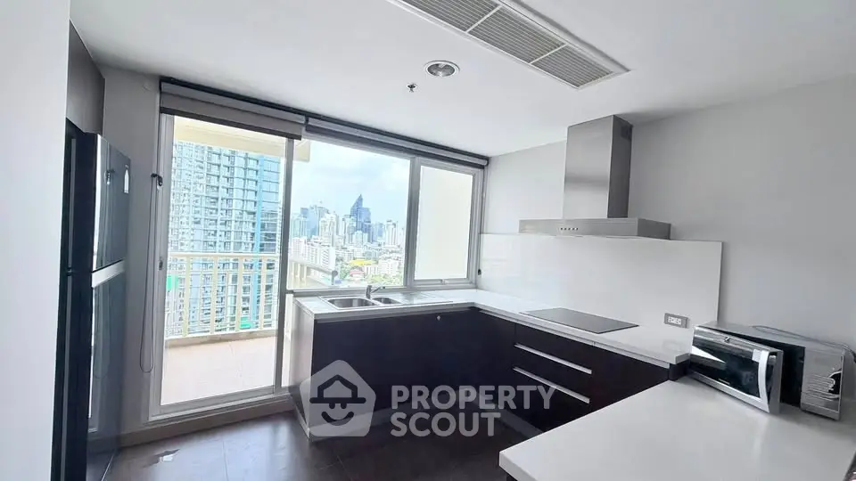 Modern kitchen with city view and balcony access in high-rise apartment