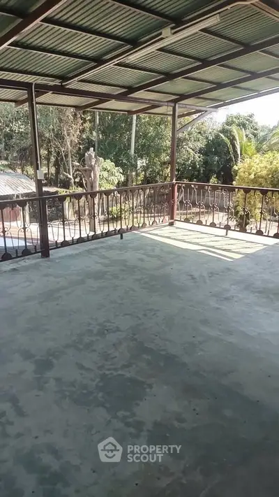 Spacious covered balcony with scenic garden view, perfect for relaxation and outdoor gatherings.