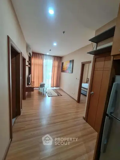 Spacious living room with wooden flooring and modern decor in a stylish apartment.