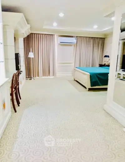 Spacious bedroom with elegant decor and large windows for natural light.