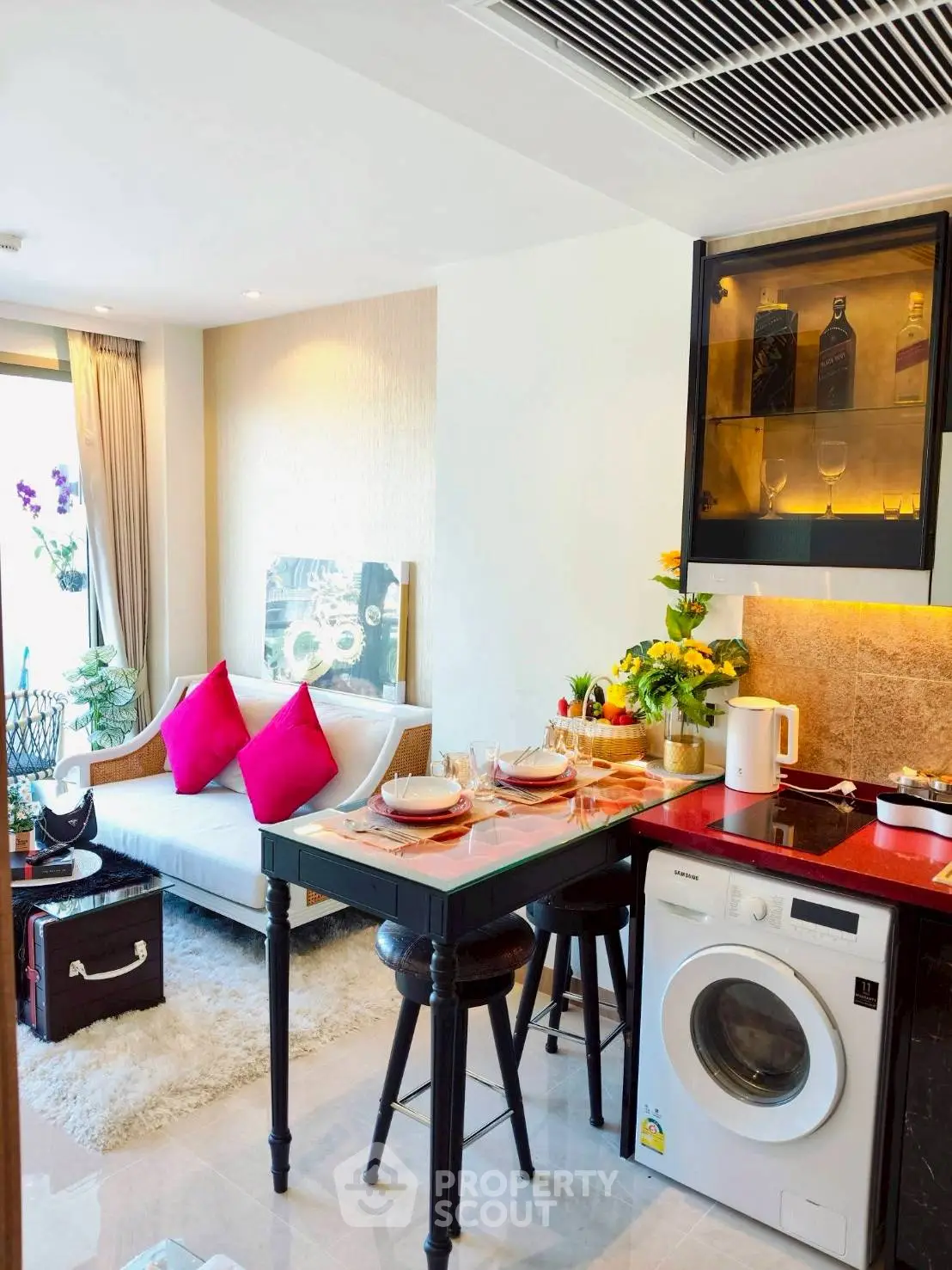 Modern open-layout living room with kitchen, featuring washing machine and stylish decor.