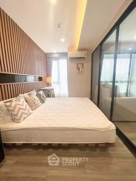 Modern bedroom with stylish wood paneling and large glass sliding doors.