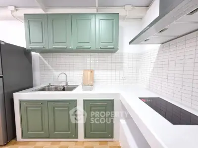 Modern kitchen with green cabinets and sleek white countertops