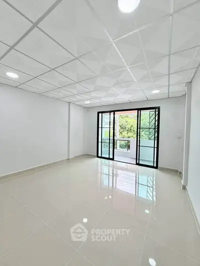 Spacious empty room with large windows and balcony, featuring modern tiled flooring and ceiling lights.