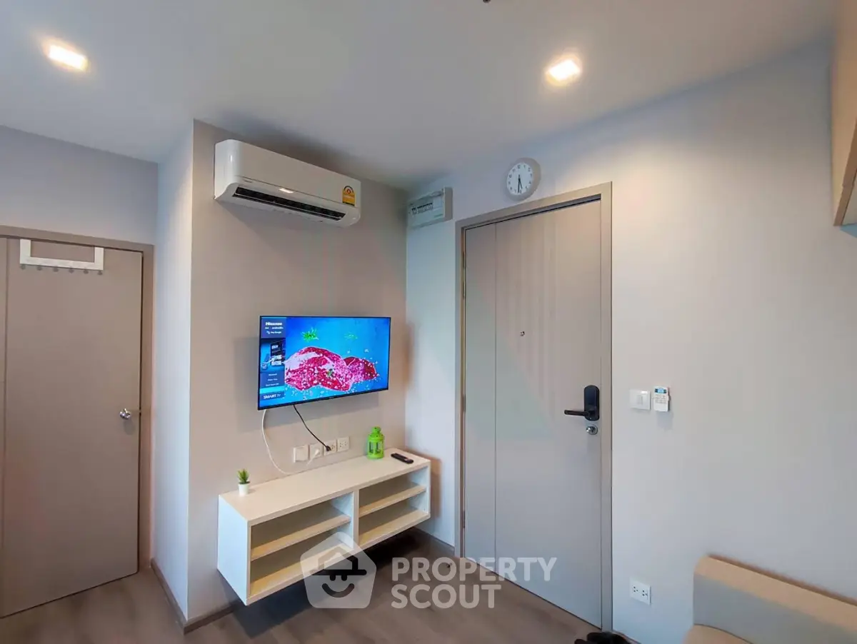 Modern living room with wall-mounted TV and air conditioning in a cozy apartment.