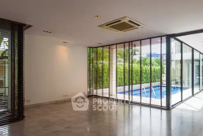 Spacious living room with pool view and floor-to-ceiling windows in modern home.