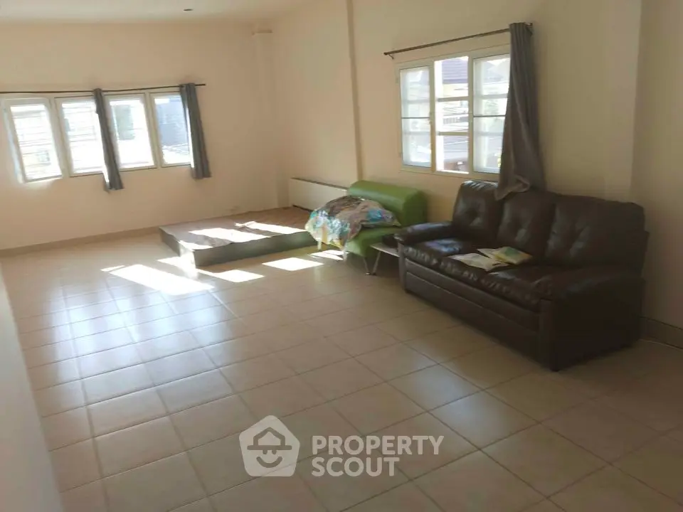Spacious living room with tiled flooring and large windows for natural light.