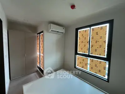 Bright bedroom with air conditioning and large windows, perfect for cozy living.