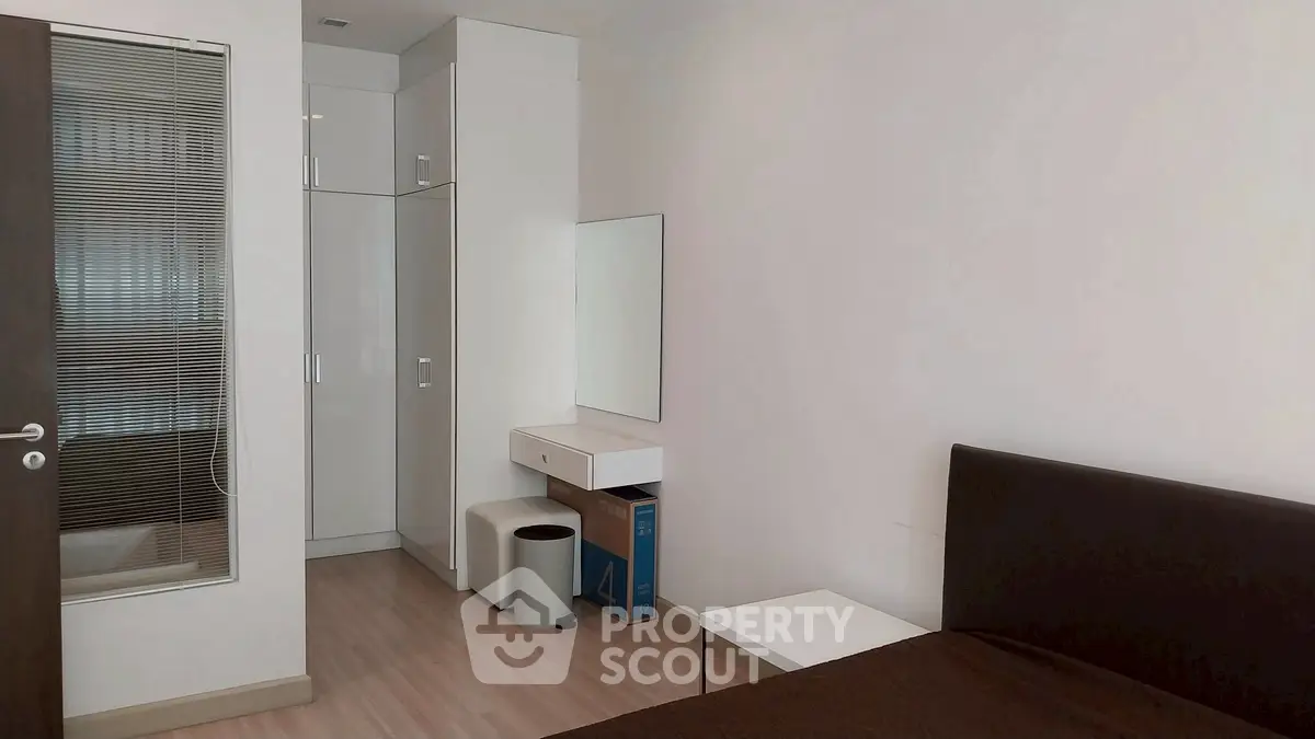 Modern minimalist bedroom with sleek furniture and ample storage space.