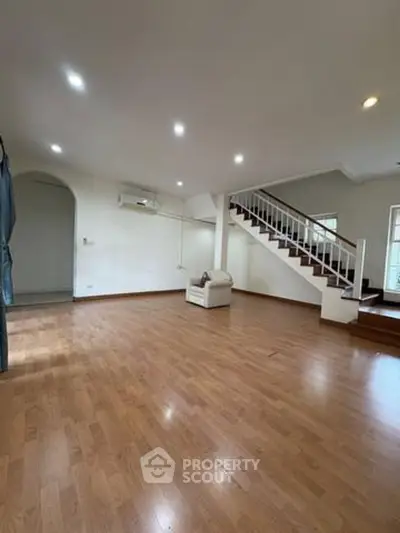 Spacious living room with wooden flooring and staircase in modern home