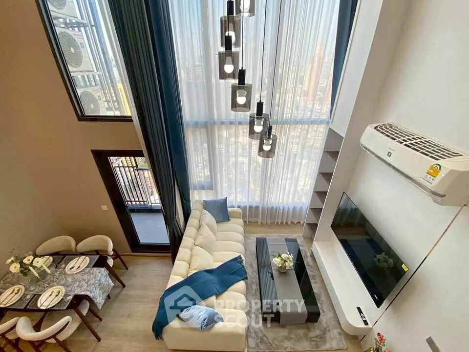 Stunning modern living room with high ceilings and elegant decor, featuring a cozy dining area and balcony access.