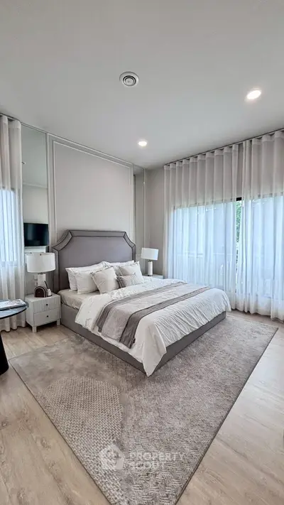 Elegant bedroom with modern decor and large windows, featuring a cozy bed and stylish furnishings.