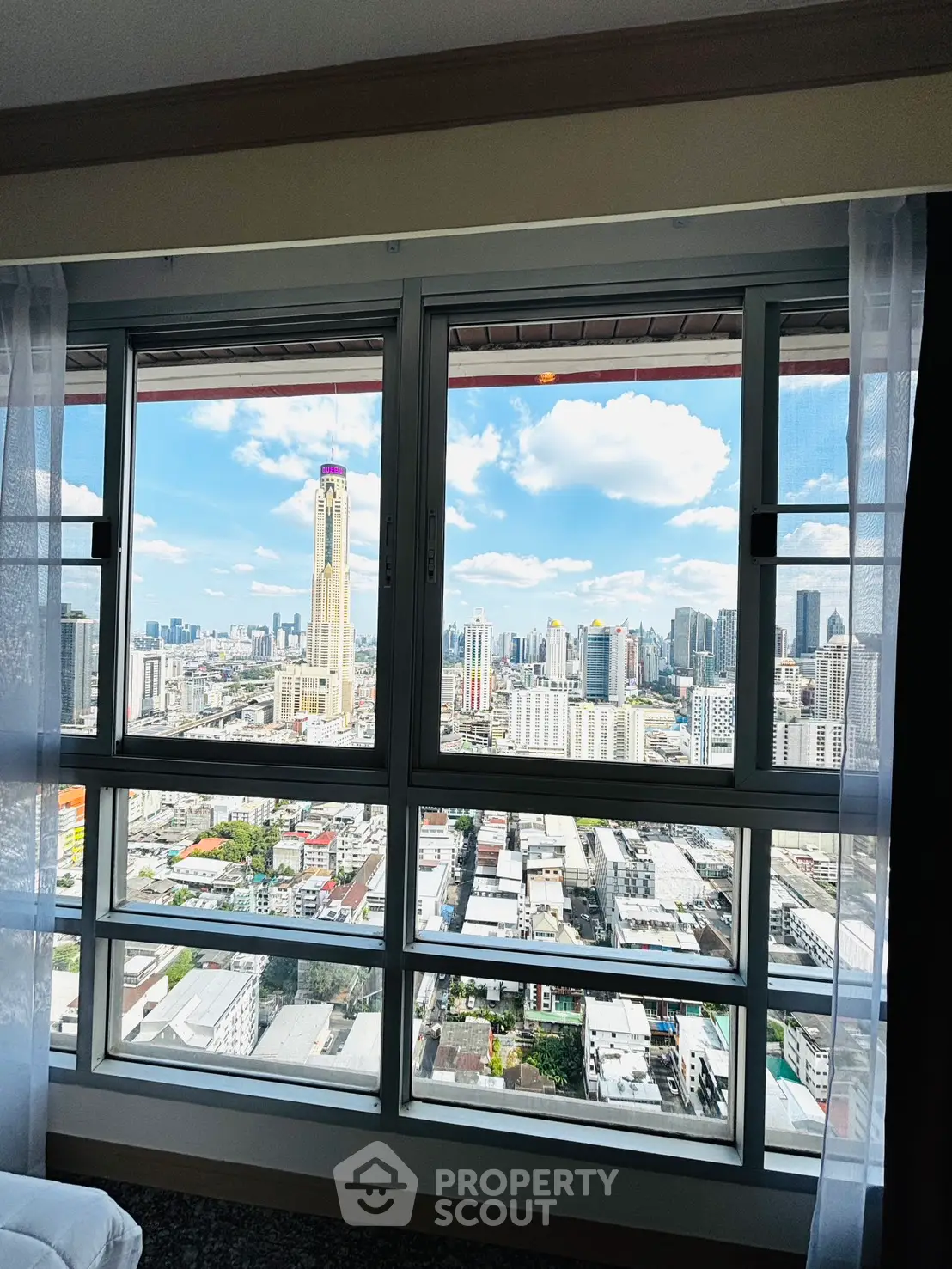 Stunning cityscape view from high-rise apartment window with clear blue skies.