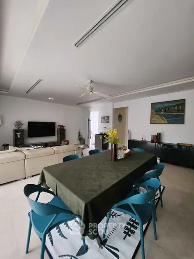 Spacious living room with modern decor and dining area, featuring stylish furniture and natural lighting.