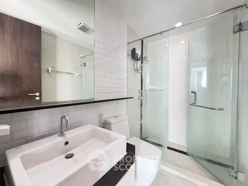 Modern bathroom with glass shower and sleek fixtures in contemporary apartment.