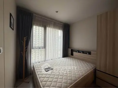 Modern bedroom with large window and stylish wooden furniture in a cozy apartment.