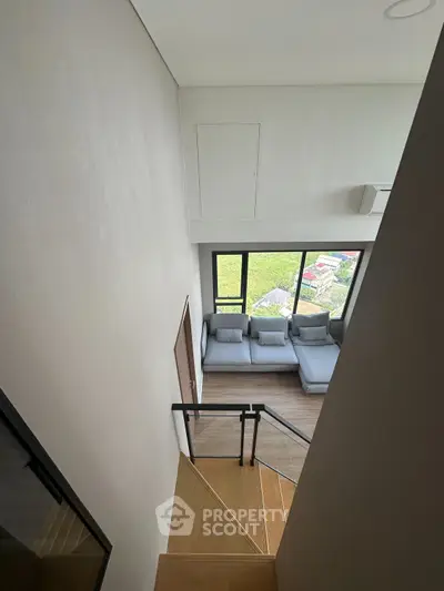 Modern duplex living room with large windows and stylish staircase