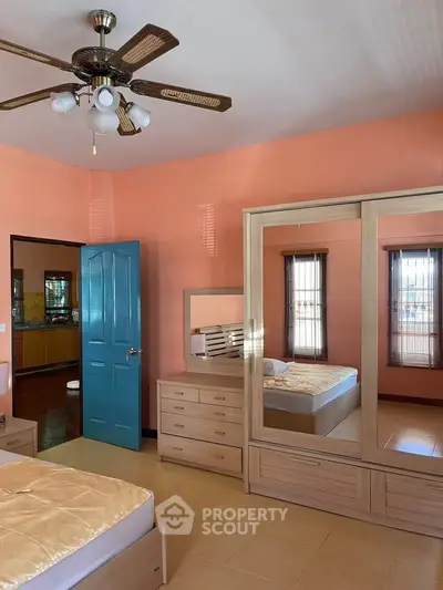 Spacious bedroom with mirrored wardrobe and ceiling fan in cozy home.