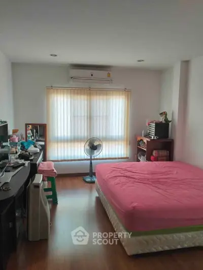 Cozy bedroom with pink bedding, air conditioning, and ample natural light from large window.