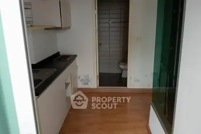 Compact kitchen with wooden flooring and adjacent bathroom in modern apartment