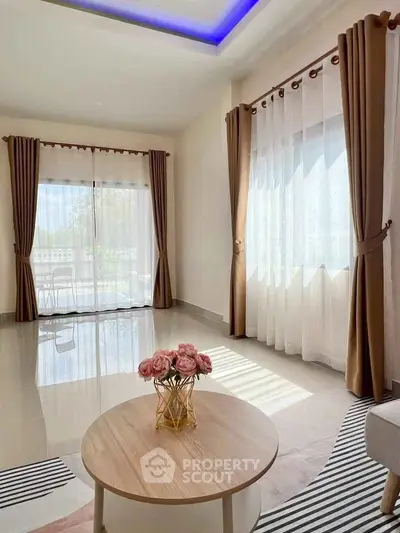 Bright living room with large windows and elegant curtains, featuring a stylish coffee table.