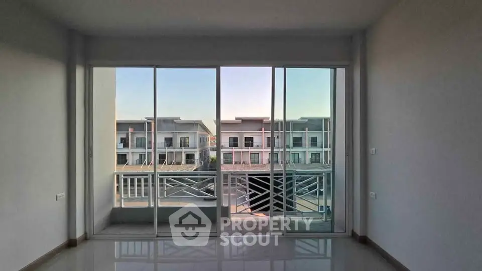 Spacious living room with large windows offering a stunning view of modern townhouses.