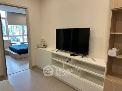 Modern living room with sleek TV unit and city view from adjacent bedroom.
