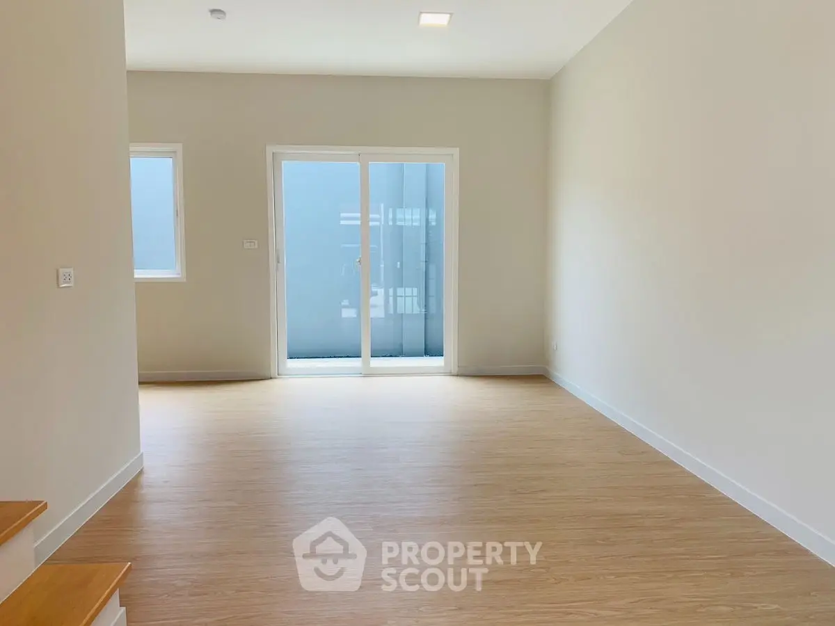 Spacious empty room with wooden flooring and large windows