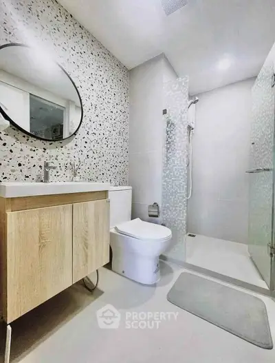 Modern bathroom with terrazzo wall, sleek vanity, and glass shower enclosure.