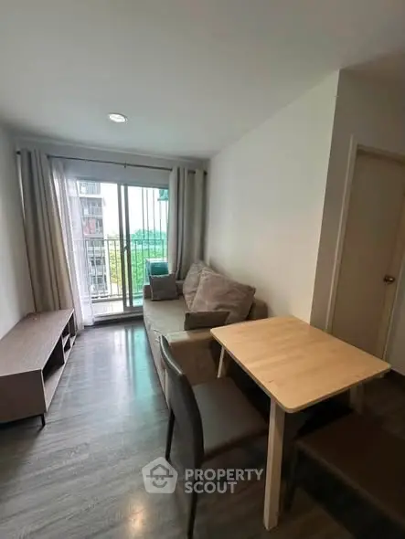 Cozy living room with modern furniture and large window offering natural light and city view.